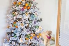 a whimsical flocked Christmas tree decorated with flowers and citrus and citrus slices plus lights