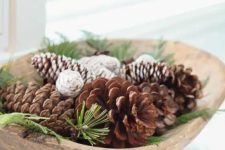 a wooden bowl with evergreens and pinecones is a lovely Christmas arrangement that can be used as a centerpiece