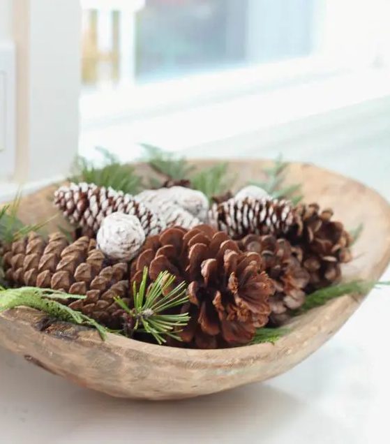 a wooden bowl with evergreens and pinecones is a lovely Christmas arrangement that can be used as a centerpiece