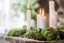 a wooden dough bowl with moss and brussels sprouts plus tall and thin candles is a beautiful Christmassy arrangement