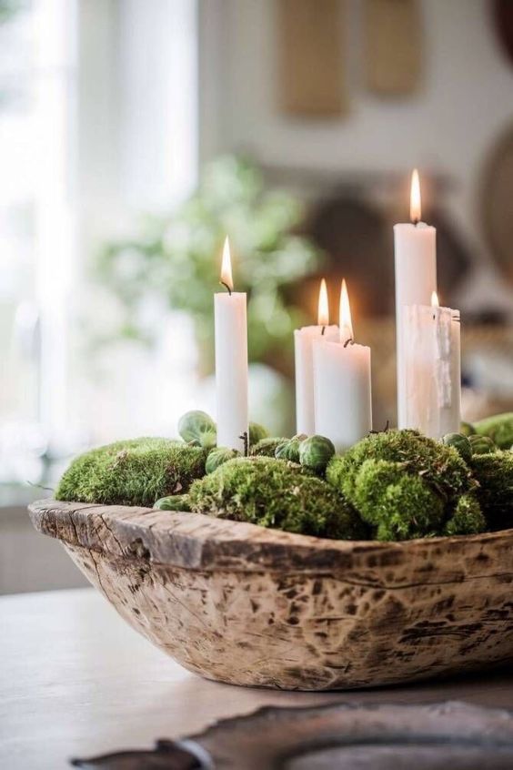 a wooden dough bowl with moss and brussels sprouts plus tall and thin candles is a beautiful Christmassy arrangement