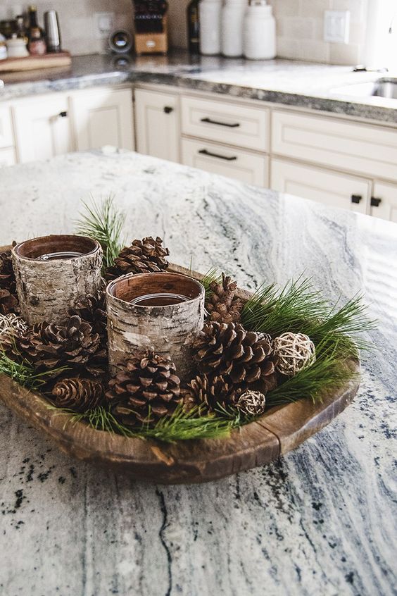 a woodland Christmas centerpiece of a dough bowl, evergreens, pinecones, candle glasses wrapped with bark