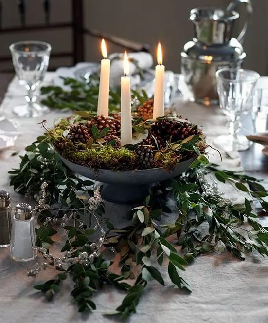a woodland Christmas centerpiece of a metal bowl with pinecones, candles, moss and greenery is a lovely idea
