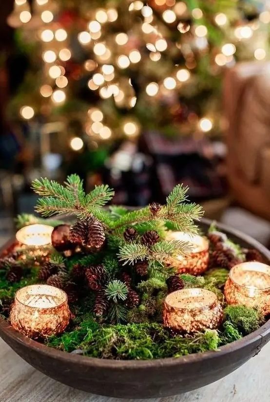 a woodland Christmas centerpiece of a wooden bowl, moss, pinecones and candles is a lovely piece you can make