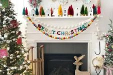 an out of the box Christmas mantel with colorful bottle cleaner trees, mini houses, an arrangement of mini wreaths and colorful pompom garlands