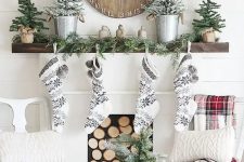 black and white stockings, snowy evergreen trees, an evergreen garland and a wooden Christmas clock