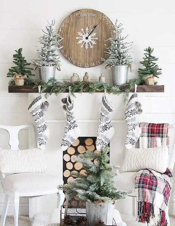 black and white stockings, snowy evergreen trees, an evergreen garland and a wooden Christmas clock