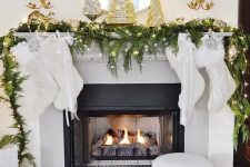 chic Christmas mantel decor with an evergreen and light garland, gold Christmas trees and a gold and silver decoration on the mirror