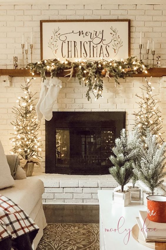 farmhouse Christmas decor with evergreens, Christmas trees potted, antlers, sotckings and a sign