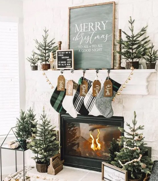 modern farmhouse Christmas decor with plaid stockings, gold bells, mini trees in baskets and crates and a house stand for firewood