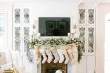 neutral stockings, a snowy evergreen garland with copper ornaments and candles for a chic look