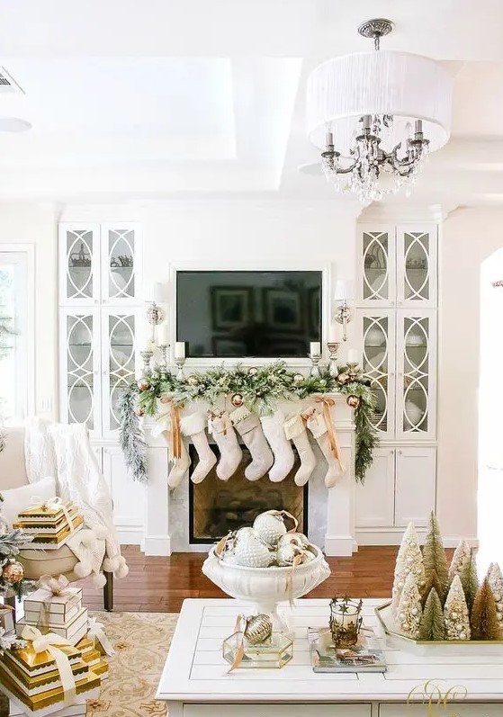 neutral stockings, a snowy evergreen garland with copper ornaments and candles for a chic look