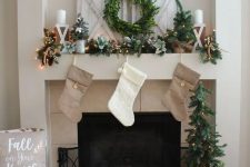 neutral stockings, an evergreen garland with lights, a wreath and some candles for pretty styling with a rustic feel