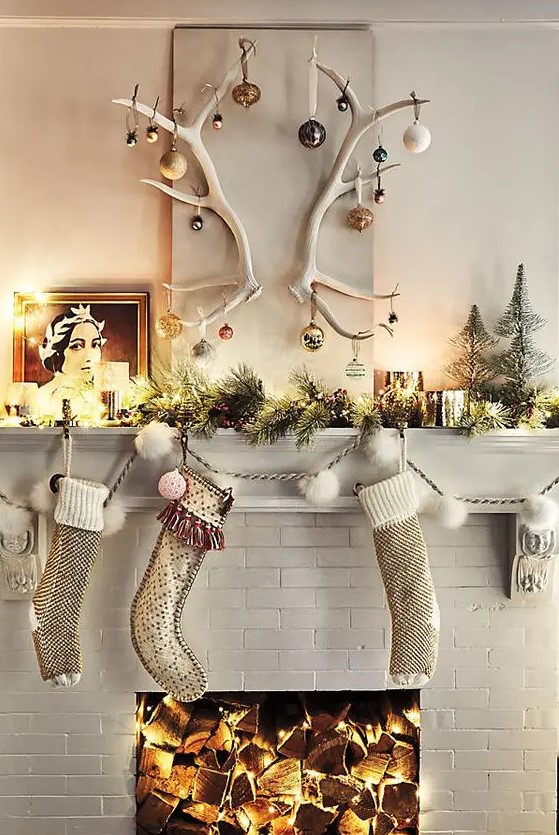 some stockings, an evergreen garland with lights, candles and antlers with Christmas ornaments