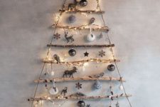 13 graduated tree branches are hung by jute, wrapped with string lights and decorated with ornaments