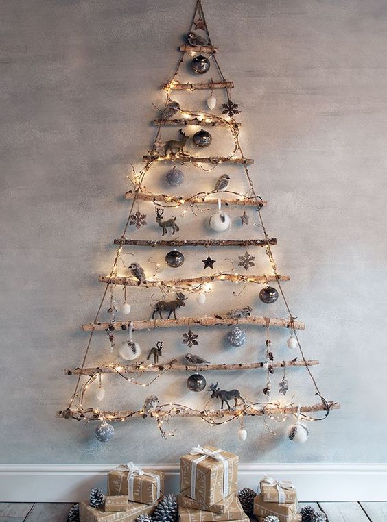 graduated tree branches are hung by jute, wrapped with string lights and decorated with ornaments