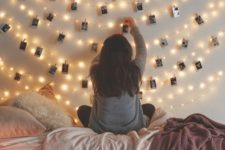 15 string lights over the bed and photos attached to them