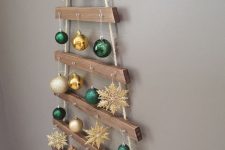 a classy hanging Christmas tree of wood and gold and green baubles and snowflakes is lovely