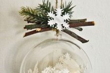 a clear Christmas ornament with paper snowflakes, branches and evergreens on top is a cool and catchy idea