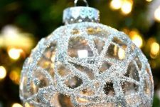 a clear glass Christmas ornament decorated with silver patterns is a shiny and cool decor idea for a Christmas tree