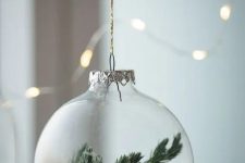 a clear glass Christmas ornament with faux snow and evergreens is a dreamy winter-inspired decor idea