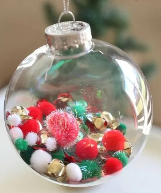 a clear glass Christmas ornament with white, red, green pompoms and gold bells is a cool decor idea done in the traditional colors