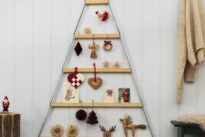 a cool wall-mounted Christmas tree composed of ledges hanging, with various decor and cards is a simple and cool idea for the holidays