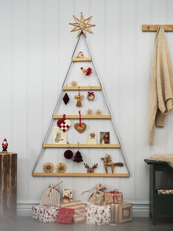 A cool wall mounted Christmas tree composed of ledges hanging, with various decor and cards is a simple and cool idea for the holidays