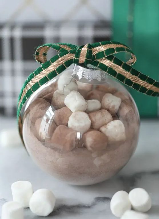 a hot cocoa Christmas ornament topped with a green and gold ribbon bow is a cool gift and decoration for the holidays