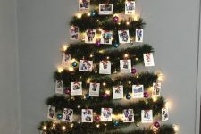 a lovely wall-mounted Christmas tree of green tinsel, lights, colorful ornaments and photos plus a star topper