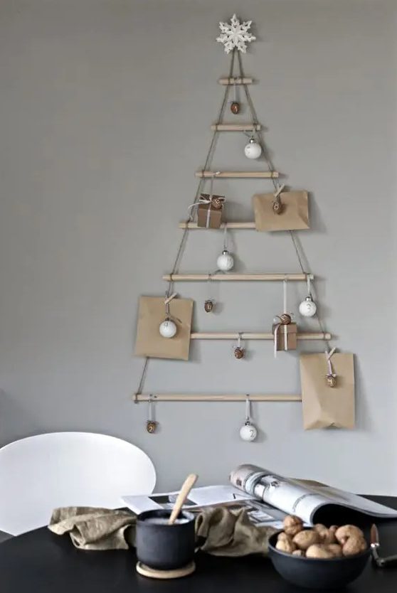 A modern wall mounted Christmas tree of sticks hanging, with ornaments and gifts, is a cool solution