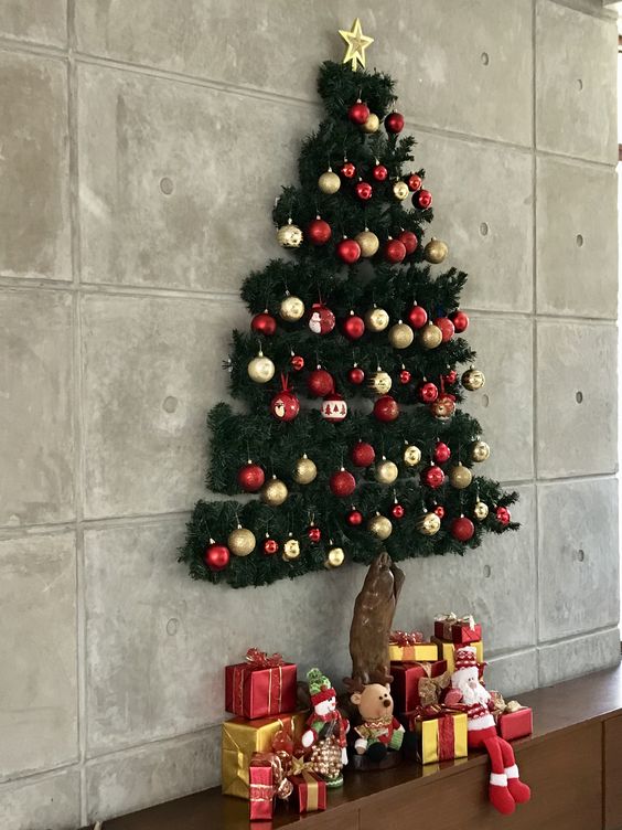 A pretty 3D wall mounted Christmas tree of evergreens, red and gold ornaments and a heart on top is amazing