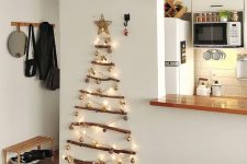 a small and pretty wall-mounted Christmas tree of branches, lights and small ornaments plus a star topper