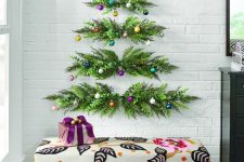 a wall-hanging Christmas tree of greenery and colorful ornaments is a nice fit for any space with some color