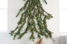 a wall-mounted Christmas tree featuring a natural silhouette and made of real branches, decorated with various ornaments