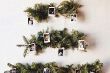 a wall-mounted Christmas tree of evergreens and photos is a cool and cozy idea with a personalized touch