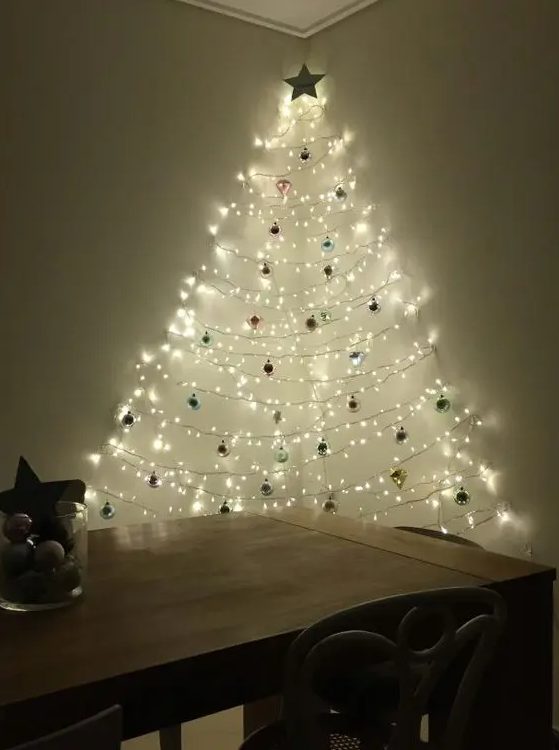 A wall mounted Christmas tree of lights and ornaments created between two walls to make it dimensional