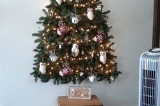 a wall-mounted Christmas tree that is 3D, with owl, mitten and bell ornaments and lights is adorable