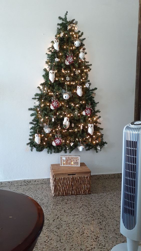 A wall mounted Christmas tree that is 3D, with owl, mitten and bell ornaments and lights is adorable