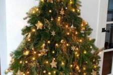 a wall-moutned Christmas tree reminding of a real one, with lights, gold ornaments and snowflakes
