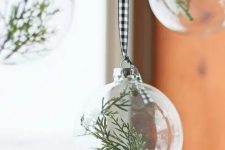 clear glass Christmas ornaments with greenery on buffalo check ribbons are great for adding an airy touch to the space