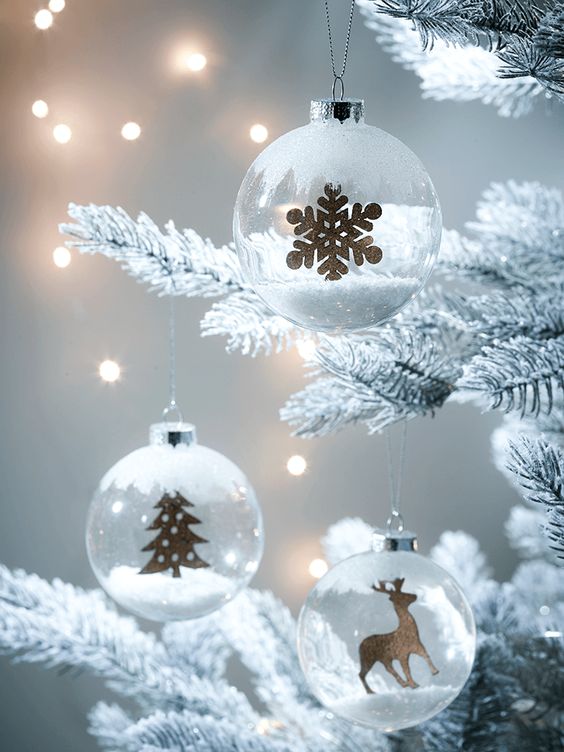 clear glass Christmas ornaments with little wooden figurines and faux snow are amazing to style a tree