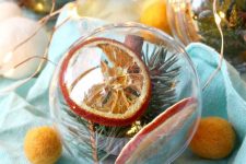 clear glass ornaments filled with dried citrus and cinnamon, evergreens are amazing to style a Christmas tree
