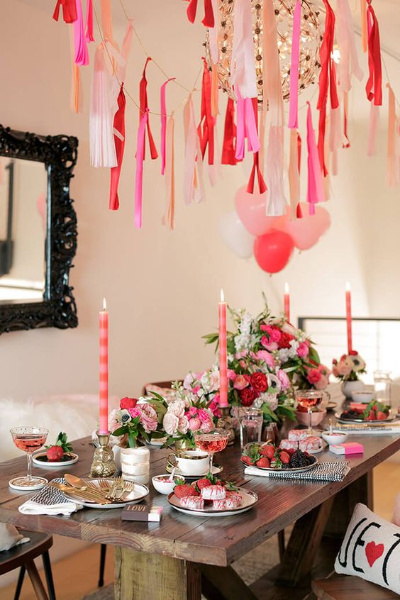 colorful galentine party decor with pink florals, tassels and balloons