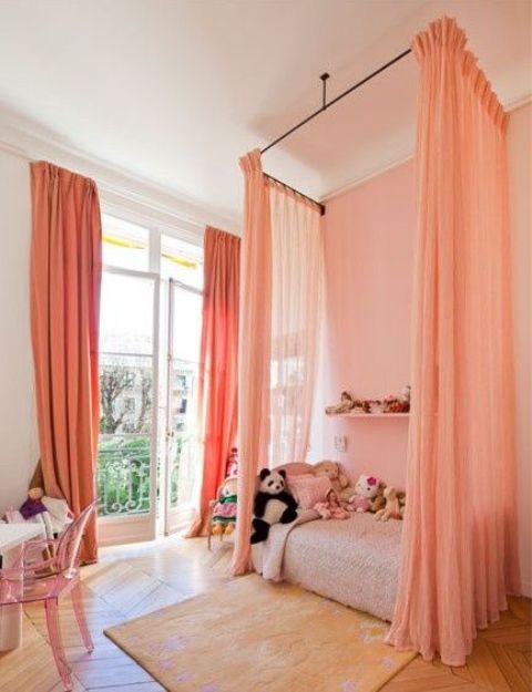 peach-colored drapes around the bed separate this area from the rest of the room