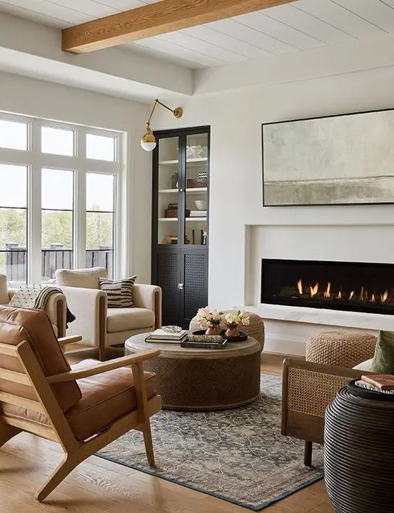 A chic modern farmhouse living room with a built in fireplace, a built in storage unit, neutral fabric and leather chairs, a sofa and some tables