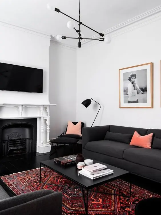 a contrasting living room with a fireplace, a couple of soot sofas, a coffee table, a chair and a floor lamp