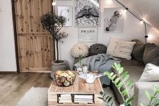 a cozy boho attic living room with a sectional, a pallet table, layered rugs, a gallery wall, string lights and a crochet ottoman