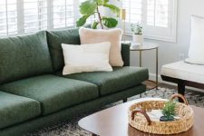 a neutral living room with a green sofa, a tan and a white chair, a coffee table and some potted greenery is welcoming