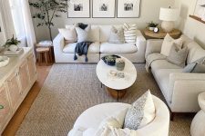 a neutral small living room with a cane TV unit, neutral sofas, a chair, a coffee table, a gallery wall and some decor and plants